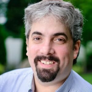 Close-up portrait of search engine journalist and RustyBrick president Barry Schwartz smiling in a striped shirt outdoors.