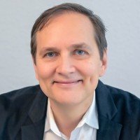 Headshot portrait of SEO expert, author, and podcast host Stephan Spencer smiling in a dark jacket and white dress shirt.