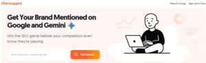 Ubersuggest homepage hero banner displaying the headline 'Get Your Brand Mentioned on Google and Gemini' with an SEO search bar and cartoon illustration of a person working on a laptop.